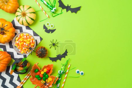 Téléchargez les photos : Halloween party concept. Pumpkin, candy and decorations on green background. Top view, flat lay - en image libre de droit