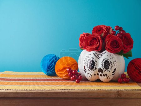 Téléchargez les photos : Jour de la mort concept de vacances. Crâne de sucre Halloween citrouille et décorations mexicaines de fête sur table en bois sur fond bleu - en image libre de droit