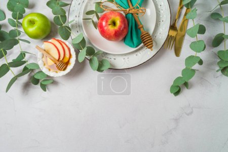 Foto de Fiesta judía Rosh Hashaná mesa festiva con plato, miel, manzana y hojas de eucalipto sobre fondo brillante. Vista superior, plano - Imagen libre de derechos