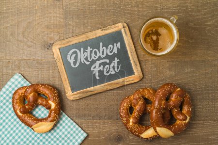 Foto de Oktoberfest concepto de fiesta con pretzel, vaso de cerveza y pizarra sobre fondo de madera. Vista superior, plano - Imagen libre de derechos