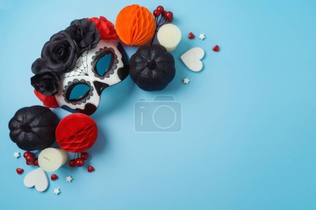 Foto de El día de la muerte concepto de fiesta mexicana. Máscara de cráneo de azúcar y decoraciones de fiesta sobre fondo azul. Vista superior, plano - Imagen libre de derechos