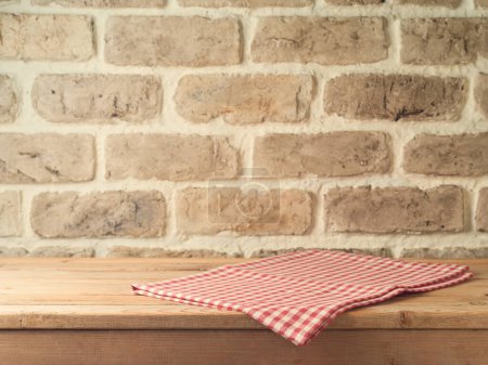 Foto de Mesa de madera vacía con mantel sobre fondo de pared de ladrillo. Simulación de la cocina para el diseño y la exhibición del producto - Imagen libre de derechos