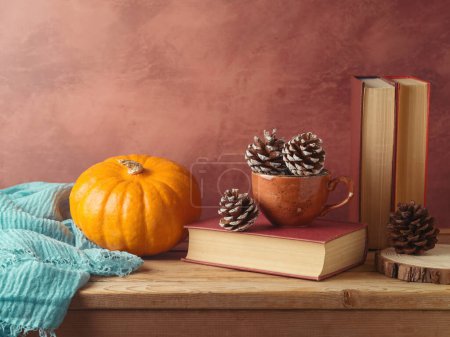 Foto de Concepto otoñal con cono de pino en taza de café, calabaza y libros sobre mesa de madera. Tarjeta de felicitación de Acción de Gracias - Imagen libre de derechos