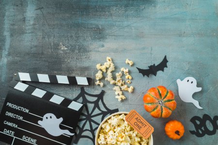 Téléchargez les photos : Soirée film d'horreur et concept de fête d'Halloween avec pop-corn, citrouille et film clapper board sur fond sombre. Vue de dessus, plan plat - en image libre de droit
