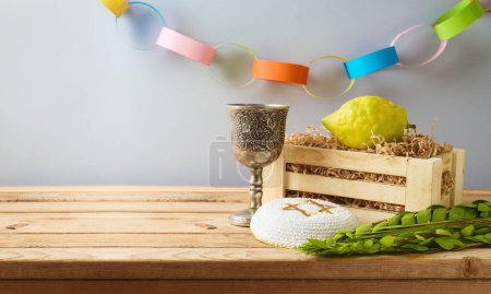 Foto de Jewish holiday Sukkot concept with traditional symbols and decorations on wooden table over gray background - Imagen libre de derechos