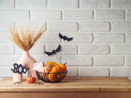 Téléchargez les photos : Fond d'Halloween avec vase moderne et décoration sur table en bois au-dessus du mur de briques. Espace vide pour l'affichage du produit - en image libre de droit
