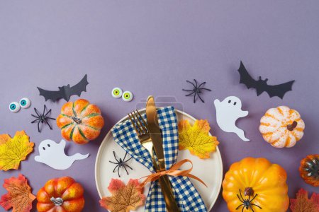 Téléchargez les photos : Concept de fête d'Halloween avec assiette, citrouille et décorations sur fond violet. Vue de dessus, plan plat - en image libre de droit