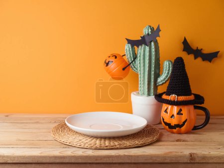 Foto de Placa vacía con alfombra de lugar en la mesa de madera sobre la pared de color naranja y decoraciones de fondo. Burla de Halloween para el diseño y la exhibición del producto. - Imagen libre de derechos