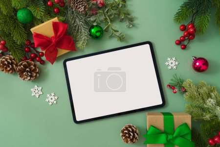 Photo for Christmas concept with digital tablet mock up, gift boxes and festive decorations on green background. Top view, flat lay - Royalty Free Image