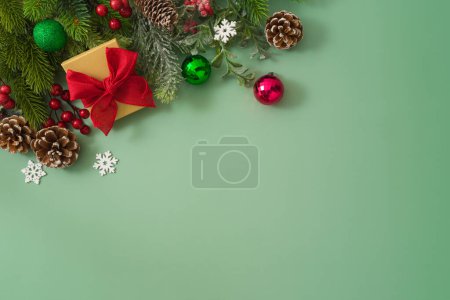 Téléchargez les photos : Concept de Noël avec coffret cadeau, branches de pins et décorations festives sur fond vert. Vue de dessus, plan plat - en image libre de droit