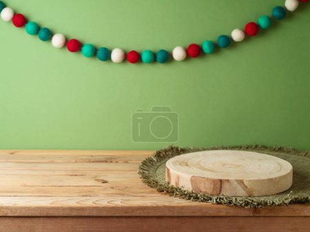 Téléchargez les photos : Panneau de bûche vide avec tapis de place sur table en bois sur fond de décoration de mur vert et guirlande. Modèle de Noël pour la conception et l'affichage des produits. - en image libre de droit