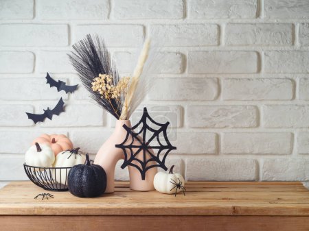 Foto de Fondo de Halloween con jarrón moderno y decoración en mesa de madera sobre pared de ladrillo - Imagen libre de derechos