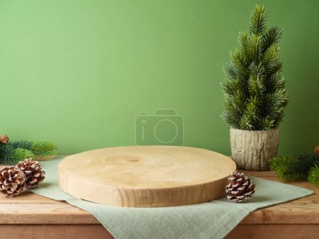Photo for Empty log podium with tablecloth on wooden table over green wall and pine tree decoration background. Christmas mock up for design and product display. - Royalty Free Image