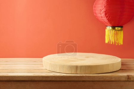 Foto de Vaciar el podio de madera en la mesa y las linternas tradicionales sobre fondo rojo. Se burlan del año nuevo chino para el diseño y la exhibición del producto. - Imagen libre de derechos
