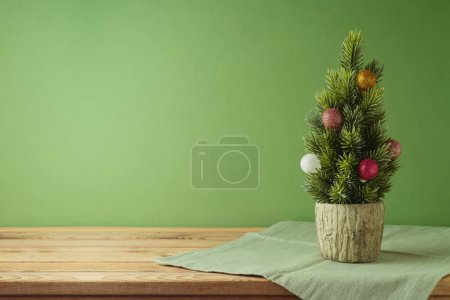 Foto de Árbol de Navidad con adorno festivo y mantel sobre mesa de madera sobre fondo verde. Cocina decoración interior - Imagen libre de derechos