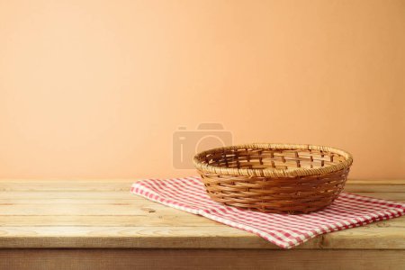 Photo for Empty basket on  table with red checked tablecloth over modern beige background.  Kitchen or bakery mock up for design and product display - Royalty Free Image