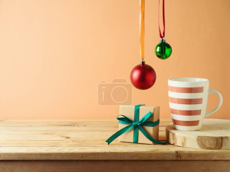 Foto de Taza de café, caja de regalo y decoración de Navidad en mesa de madera sobre fondo de pared moderno. Simulación de la cocina para el diseño y la exhibición del producto. - Imagen libre de derechos