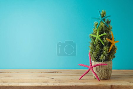 Foto de Árbol de Navidad con adornos creativos sobre mesa de madera sobre fondo azul - Imagen libre de derechos