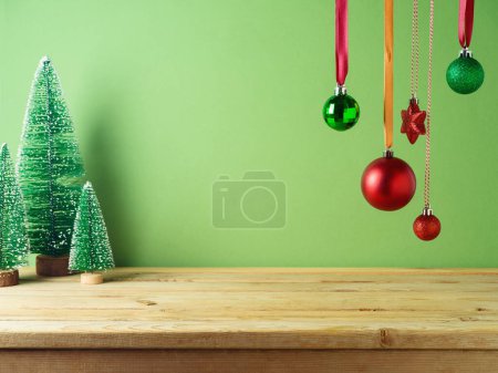 Téléchargez les photos : Table en bois vide avec décoration ornementale suspendue et pins sur fond vert. Modèle de Noël pour la conception et l'affichage des produits. - en image libre de droit