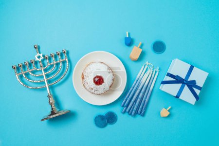 Photo for Jewish holiday Hanukkah top view composition with menorah, traditional donuts and gift box on blue background. Flat lay - Royalty Free Image