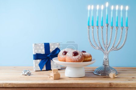 Téléchargez les photos : Noël juif Hanoukka concept avec menorah, beignets traditionnels et boîte cadeau sur table en bois. - en image libre de droit