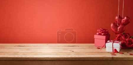 Foto de Fondo de San Valentín con mesa de madera vacía, caja de regalo y formas de corazón. Maqueta de vacaciones para el diseño y la exhibición del producto - Imagen libre de derechos