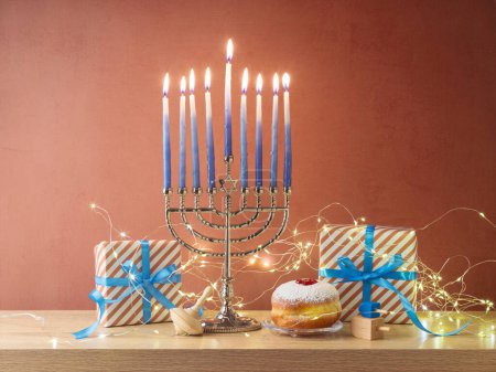 Foto de Fiesta judía fondo Hanukkah con menorah, rosquillas tradicionales y caja de regalo en mesa de madera - Imagen libre de derechos