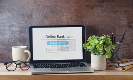 Foto de Concepto de negocio de banca en línea con computadora portátil, taza de café y planta en la mesa de oficina en casa - Imagen libre de derechos