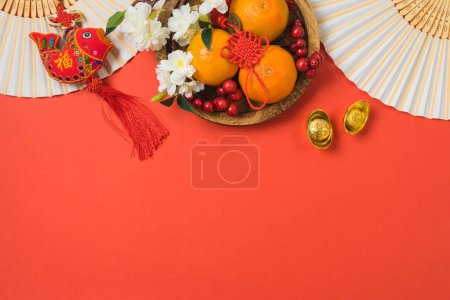 Téléchargez les photos : Célébration du Nouvel An chinois avec des décorations traditionnelles pour le festival de printemps sur fond rouge. Vue de dessus, plan plat. Texte chinois : "Fortune, bonne chance et richesse" - en image libre de droit