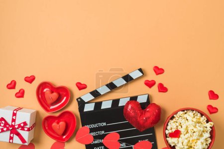 Téléchargez les photos : Joyeuse Saint-Valentin et concept de film romantique avec film clapper board, formes de coeur et pop-corn sur fond tendance. Vue de dessus, plan plat - en image libre de droit