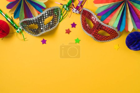 Téléchargez les photos : Concept carnaval ou mardi gras avec masques de carnaval dorés et décorations de fête sur fond jaune. Vue de dessus, plan plat - en image libre de droit