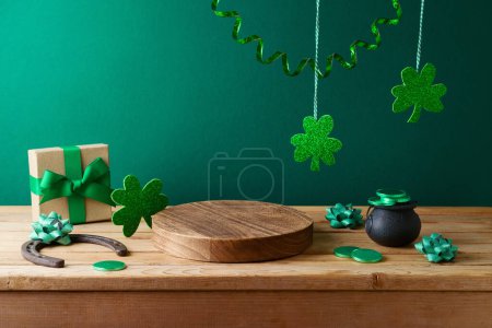 Téléchargez les photos : St Patrick's day concept with wooden log, shamrock and gift box on wooden table over green background. Holiday mock up for design and product display - en image libre de droit