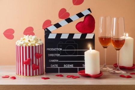 Téléchargez les photos : Happy Valentine's day et concept de film romantique avec film clapper board, formes de coeur, vin et pop-corn sur table en bois sur fond tendance - en image libre de droit