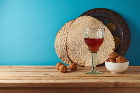 Foto de Concepto de Pascua judía con copa de vino, matzá y plato de seder en la mesa de madera sobre fondo azul. - Imagen libre de derechos