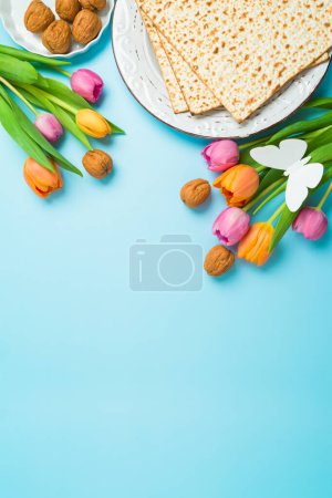Téléchargez les photos : Carte de vœux verticale Pessah des fêtes juives avec matsa et fleurs de tulipes printanières sur fond bleu. Vue de dessus, composition plate - en image libre de droit