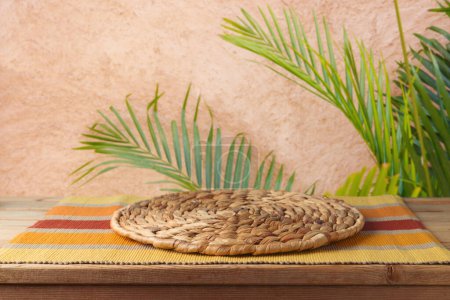 Mesa de madera vacía con alfombra de mimbre sobre la pared con fondo de palmera. Maqueta de picnic de verano para el diseño y la exhibición del producto.