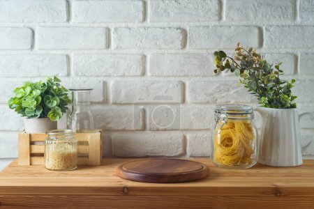 Téléchargez les photos : Grumes en bois vides sur la table de cuisine sur fond de mur de briques blanches. Modèle de cuisine pour la conception et l'affichage du produit. - en image libre de droit