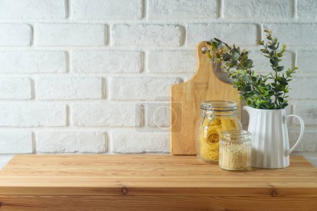 Photo for Empty wooden l table with plant, food jars and cutting board over white brick wall  background.  Kitchen mock up for design and product display. - Royalty Free Image