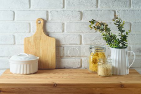 Foto de Mesa de cocina con frascos de alimentos y plantas sobre fondo de pared de ladrillo blanco. Simulación de la cocina para el diseño y la exhibición del producto. - Imagen libre de derechos