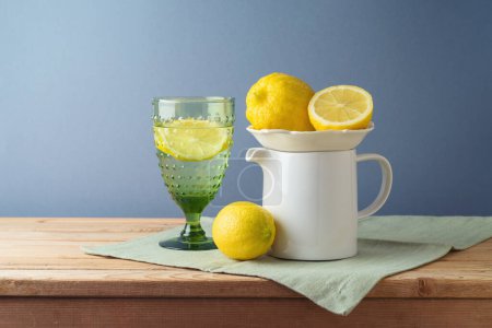 Foto de Composición de verano con limones y jarra blanca sobre mesa de madera de cocina - Imagen libre de derechos