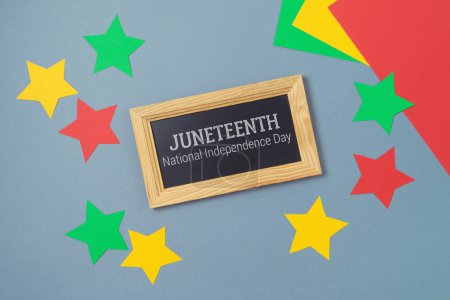 Photo for Juneteenth freedom day concept with colorful paper, blackboard and stars on gray background. Top view, flat lay - Royalty Free Image