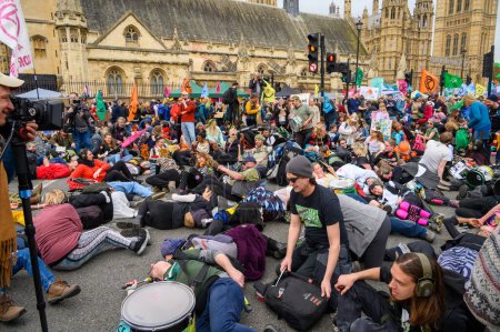 Foto de LONDRES - 22 de abril de 2023: Presenciar la poderosa Rebelión de la Extinción morir en masa mientras los manifestantes se acuestan ante las Cámaras del Parlamento, exigiendo acción climática urgente y justicia ambiental. - Imagen libre de derechos