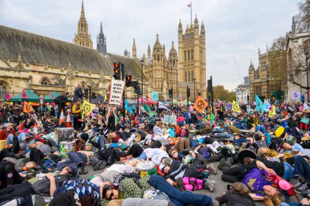 Foto de LONDRES - 22 de abril de 2023: Participar en la escena impactante de los manifestantes de XR que participan en un simulacro de muerte en masa, dejando sus cuerpos ante el Parlamento para enfatizar la necesidad de una acción climática. - Imagen libre de derechos