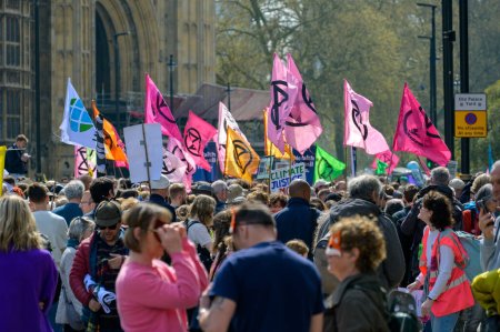 Foto de LONDRES - 22 de abril de 2023: Activismo dinámico: Las banderas de la rebelión de extinción ondean por encima de la marcha de protesta en Londres, simbolizando el llamado a la acción climática. - Imagen libre de derechos