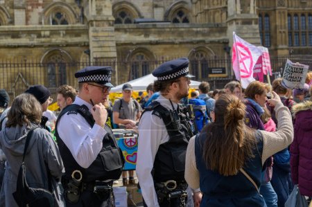 Photo for LONDON - April 22, 2023: Urban dialogue unfolds: Metropolitan police officers engage in meaningful conversation with Extinction Rebellion protesters during the London march. - Royalty Free Image