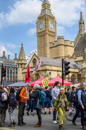 Foto de LONDRES - 22 de abril de 2023: La posición icónica de XR: Big Ben y The London Eye sirven como telones de fondo llamativos mientras los manifestantes ondean banderas XR en la protesta climática en Londres. - Imagen libre de derechos