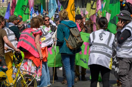 Foto de LONDRES - 22 de abril de 2023: Un motín de colores: Manifestantes de la rebelión de extinción en la manifestación de protesta XR en Londres, con un vibrante telón de fondo de coloridas banderas XR, se unen para la acción climática. - Imagen libre de derechos