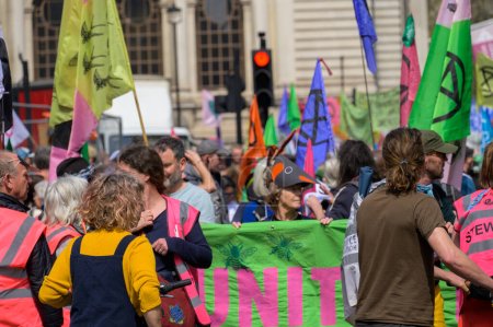 Foto de LONDRES - 22 de abril de 2023: Los defensores del clima de Londres: manifestantes de XR se reúnen en la ciudad con coloridas banderas de XR en el fondo, subrayando su dedicación a la acción climática. - Imagen libre de derechos