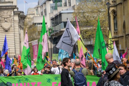 Foto de LONDRES - 22 de abril de 2023: Posición climática de Londres: Los manifestantes de XR convergen en la ciudad, en un contexto llamativo de coloridas banderas de protesta, subrayando su postura unida sobre la defensa del clima. - Imagen libre de derechos