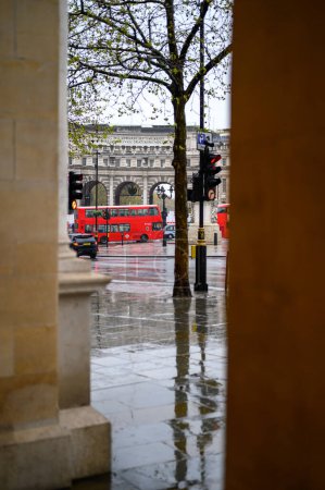 Foto de LONDRES - 24 de abril de 2023: El icónico autobús rojo de Londres añade vitalidad a un fondo lluvioso en Admiralty Arch. - Imagen libre de derechos